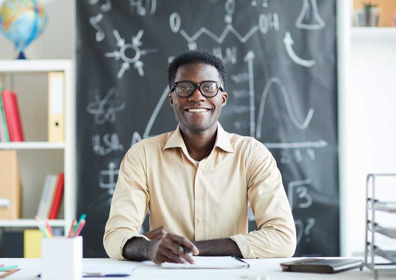 happy teacher sitting at a desk